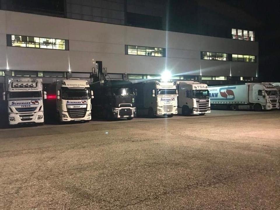 Row of HFK trucks lined up at a loading depot at night